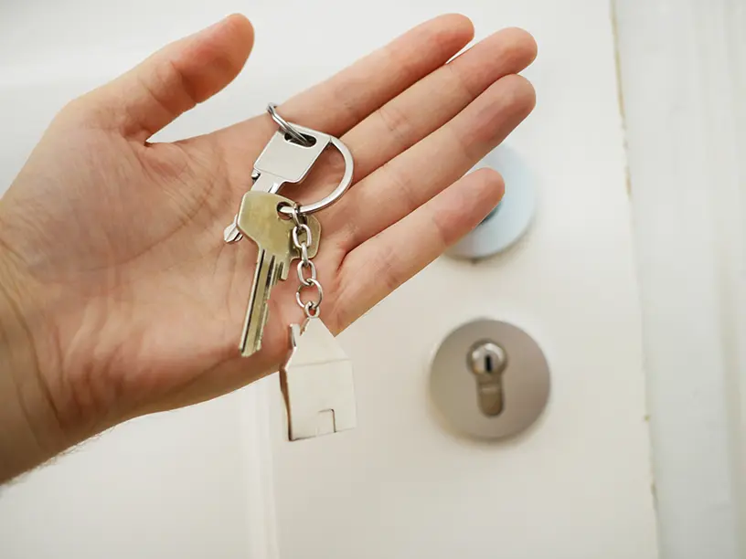 En person, der holder en nøgle til et hus.