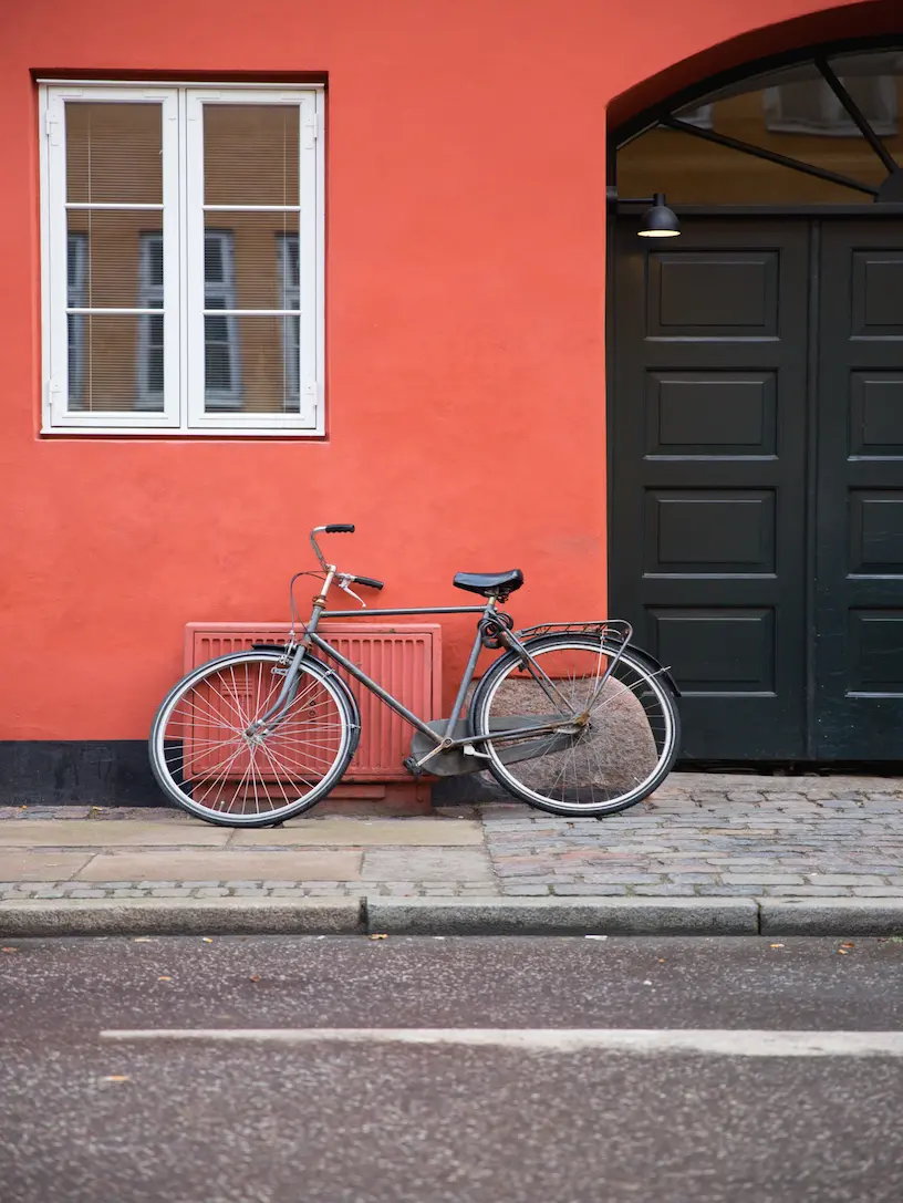 En cykel læner sig op ad en rød bygning.