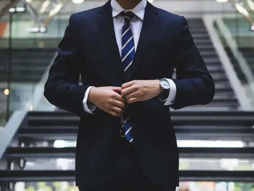 En mand i jakkesæt tilpasser sit slips, inden han skal til et møde for at diskutere finansieringsmuligheder for renovering af ejendom.