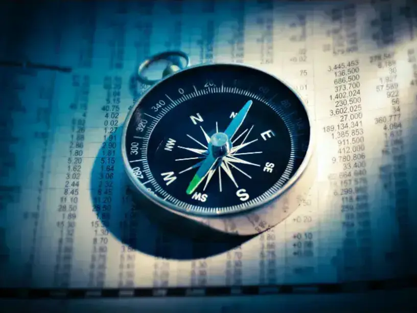 Et kompas sidder oven på et stykke papir, der symboliserer navigation til ejendomsfinansiering.