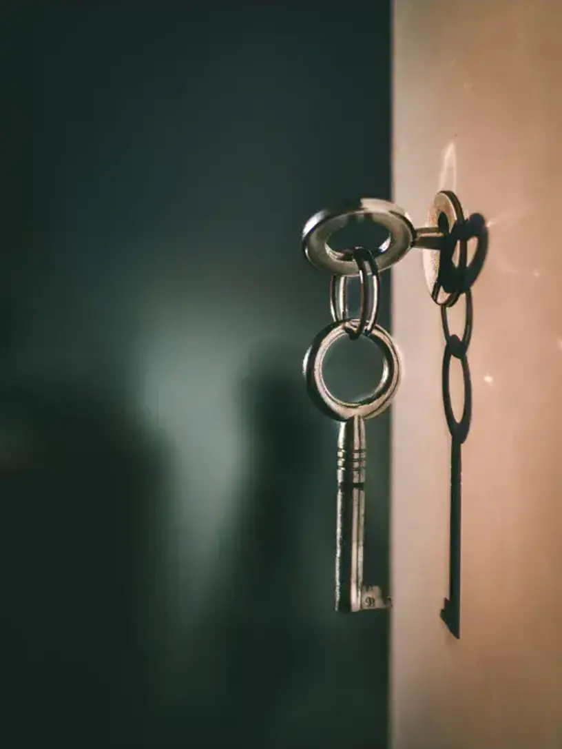 En nøgle hænger på en dør, der symboliserer ejerskabet af et hus.