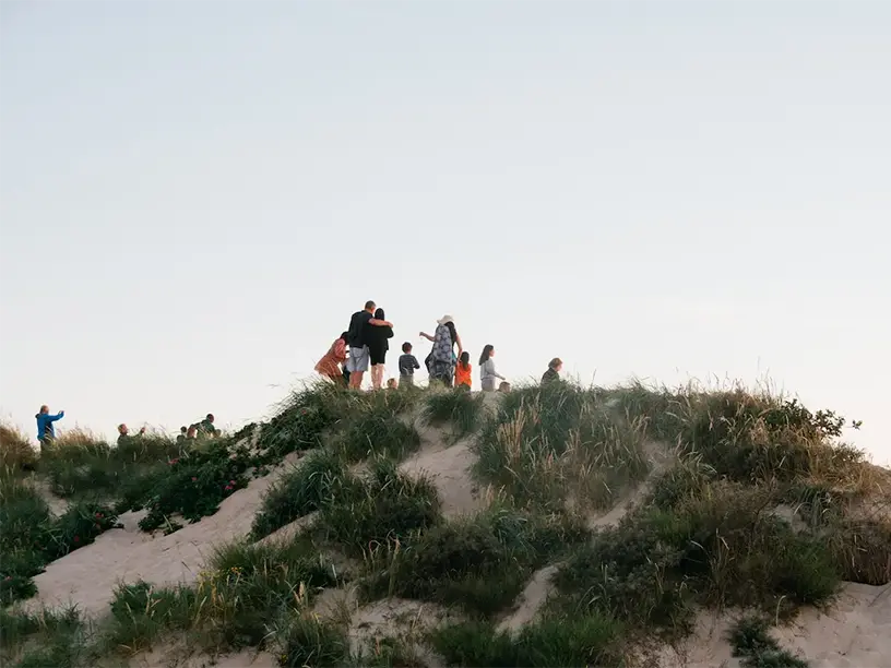 En gruppe mennesker nyder udsigten fra toppen af en klit.