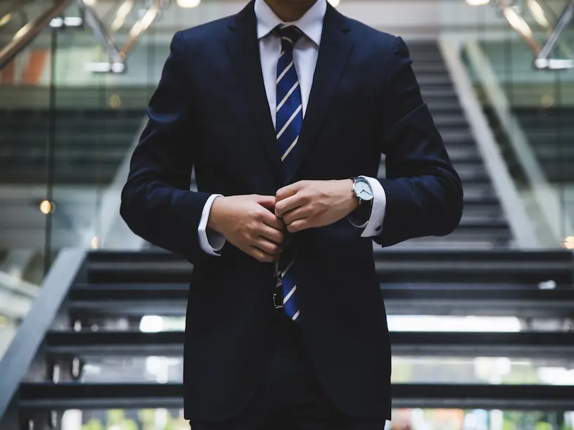 En mand i jakkesæt justerer sit slips.